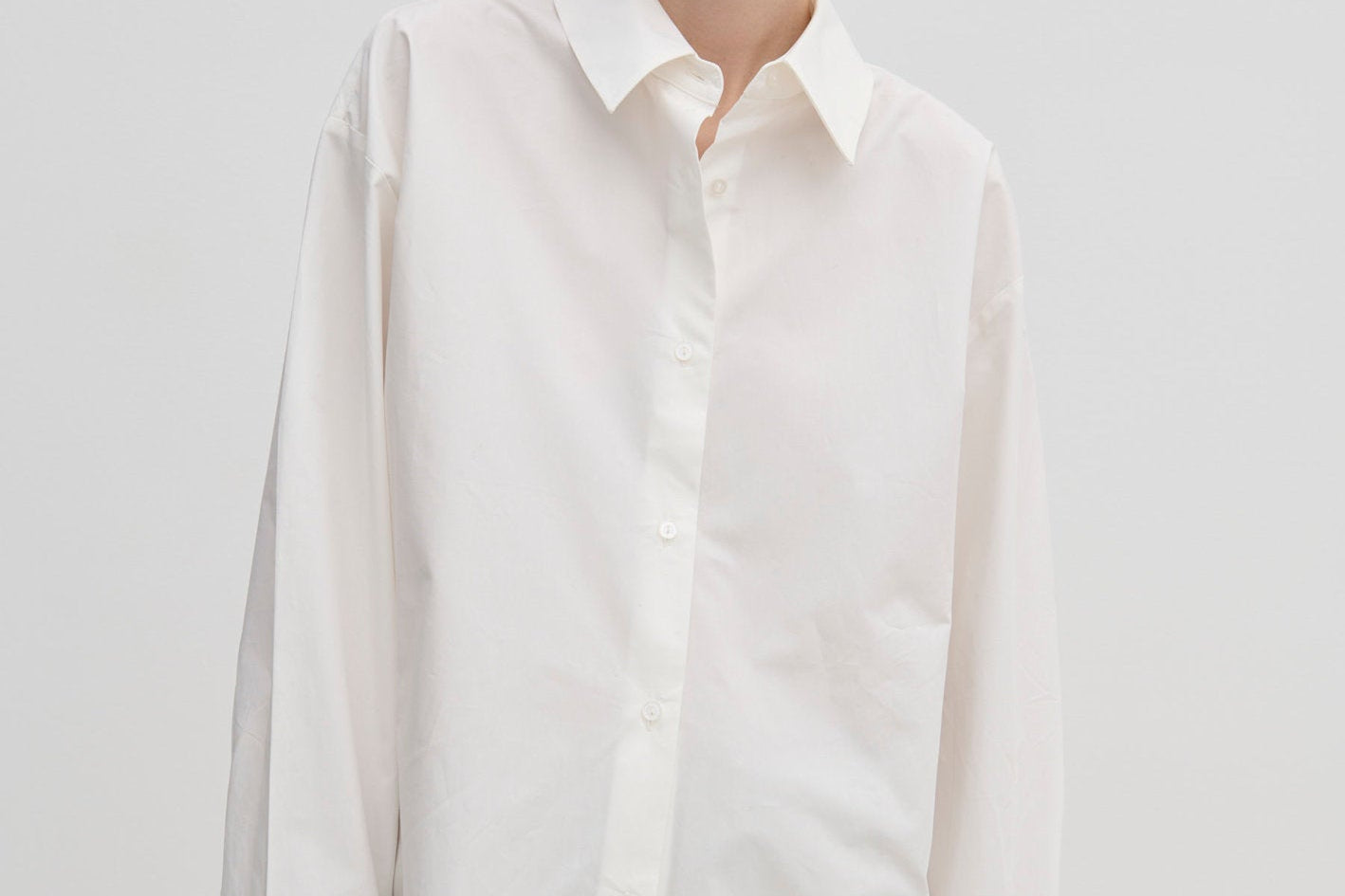 A model wears the Herskind ApS Inga Shirt, a crisp, oversized white button-down with a point collar and wide, folded cuffs.