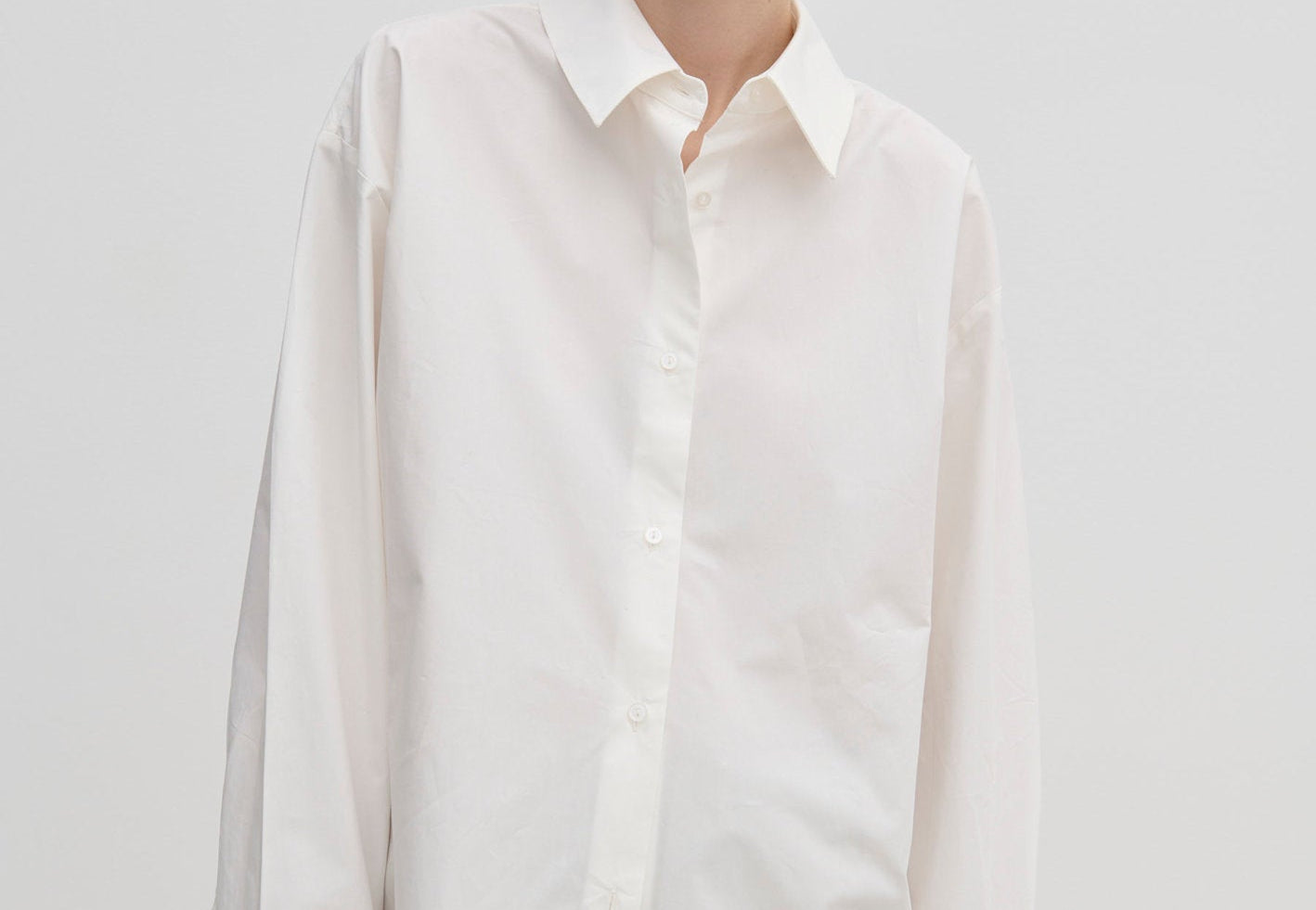 A model wears the Herskind ApS Inga Shirt, a crisp, oversized white button-down with a point collar and wide, folded cuffs.