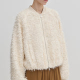 A person wears a cream-colored, relaxed-fit Jimi Bomber Jacket by Herskind ApS, featuring a textured, fringed finish and balloon sleeves.