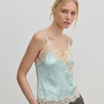 The Herskind ApS Little Top is a pale blue camisole with adjustable straps and wide beige lace trim along the neckline and hem.