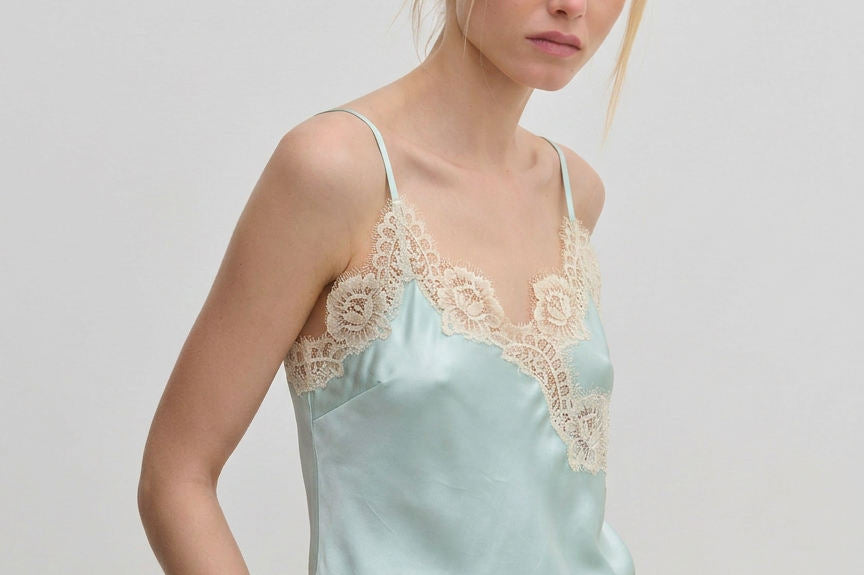 The Herskind ApS Little Top is a pale blue camisole with adjustable straps and wide beige lace trim along the neckline and hem.