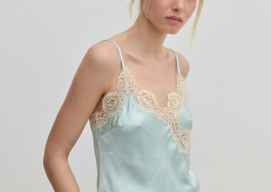 The Herskind ApS Little Top is a pale blue camisole with adjustable straps and wide beige lace trim along the neckline and hem.