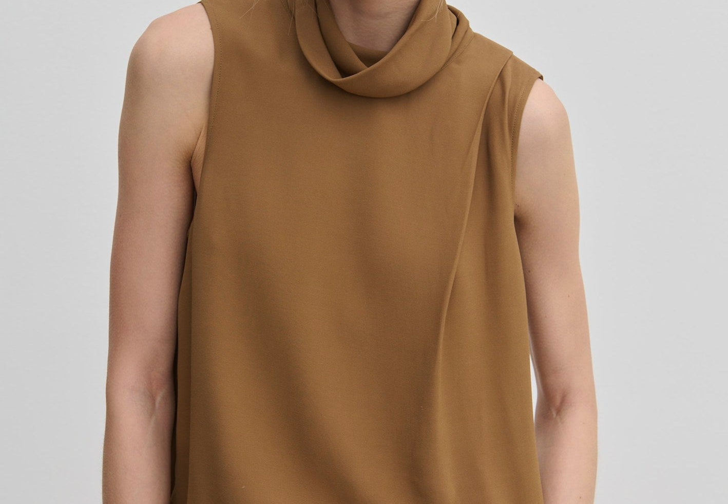 The Herskind ApS Loa Top is a sleeveless brown garment in a relaxed fit with a high, draped cowl neckline.