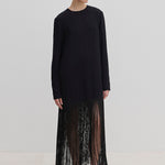 The Aris Dress by Herskind ApS is a long-sleeved black shift dress with a crew neckline and an ankle-length fringe hem, styled with black mules.
